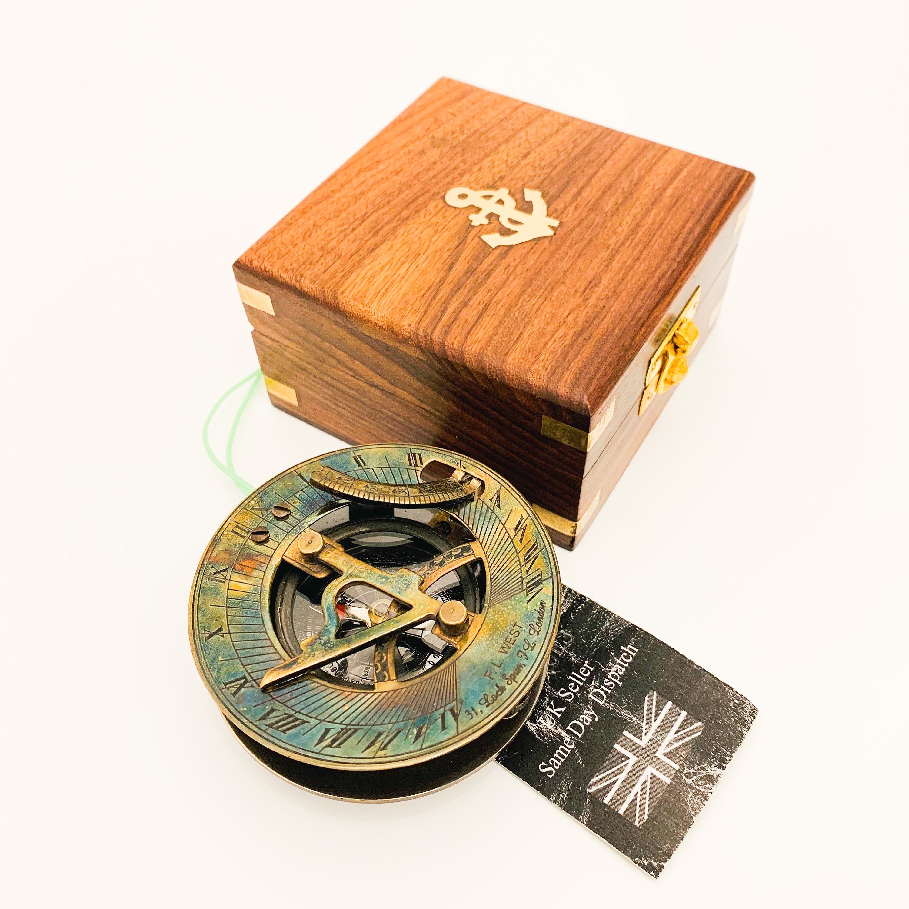 Peut inclure: Un cadran solaire en laiton avec une boussole et une loupe, dans une boîte en bois avec un motif d'ancre. Le cadran solaire a une palette de couleurs bleu, vert et or. La boîte est en bois foncé avec un loquet en laiton.