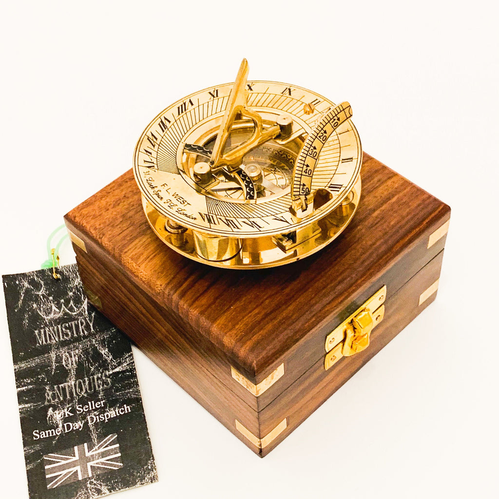 May include: A brass sundial with a compass and a wooden box. The sundial has Roman numerals and a compass rose. The box is made of dark wood with brass accents.