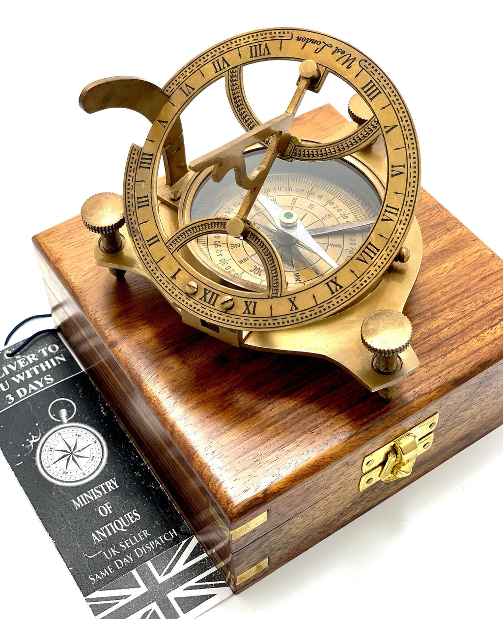 May include: A brass sundial and compass set in a wooden box. The sundial features Roman numerals and a compass rose. The box is made of dark wood with brass hinges and a latch.