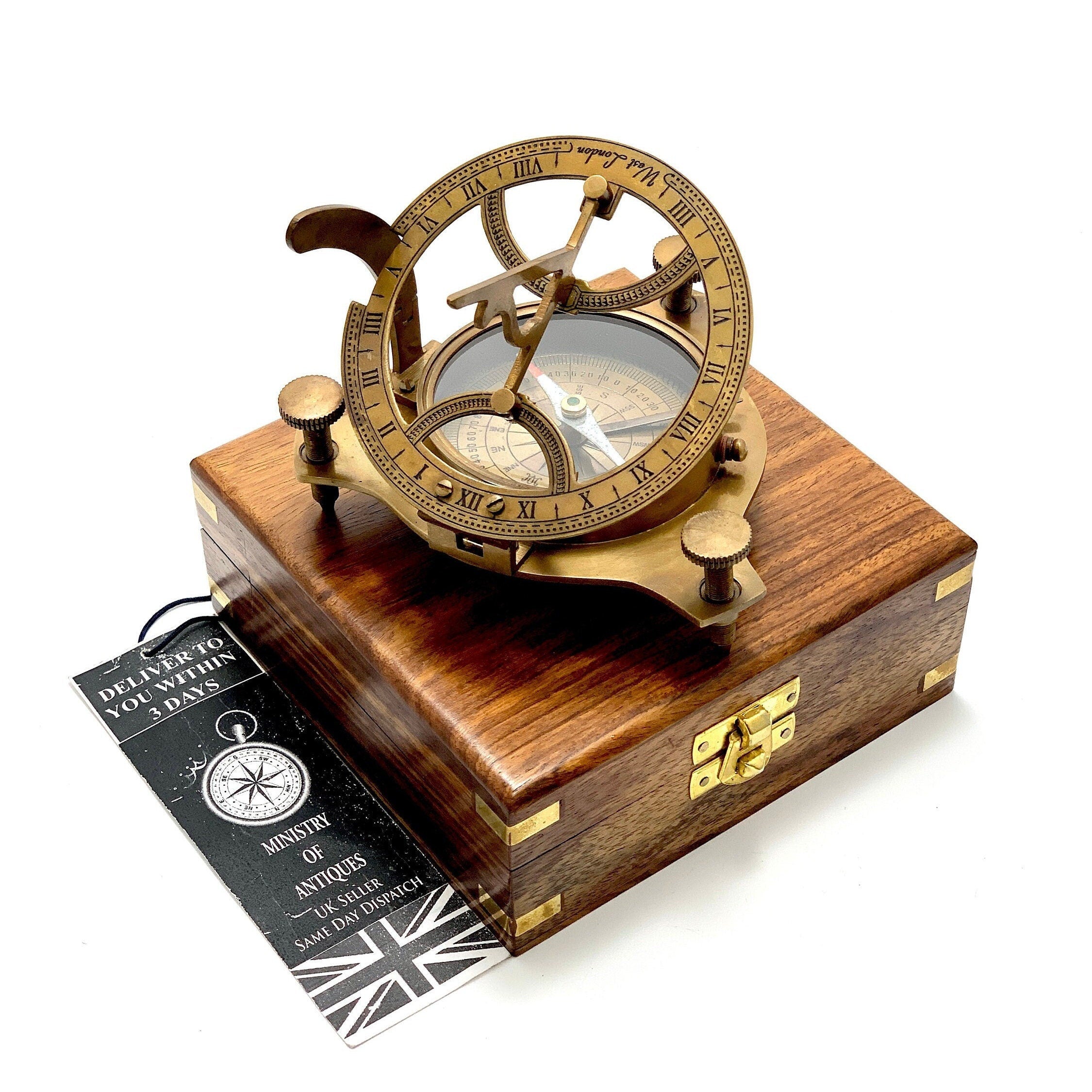 May include: A brass compass and sundial set in a wooden box. The compass features a clear face with a compass rose and a needle. The sundial has Roman numerals and a brass pointer. The box is made of dark wood with a brass latch.