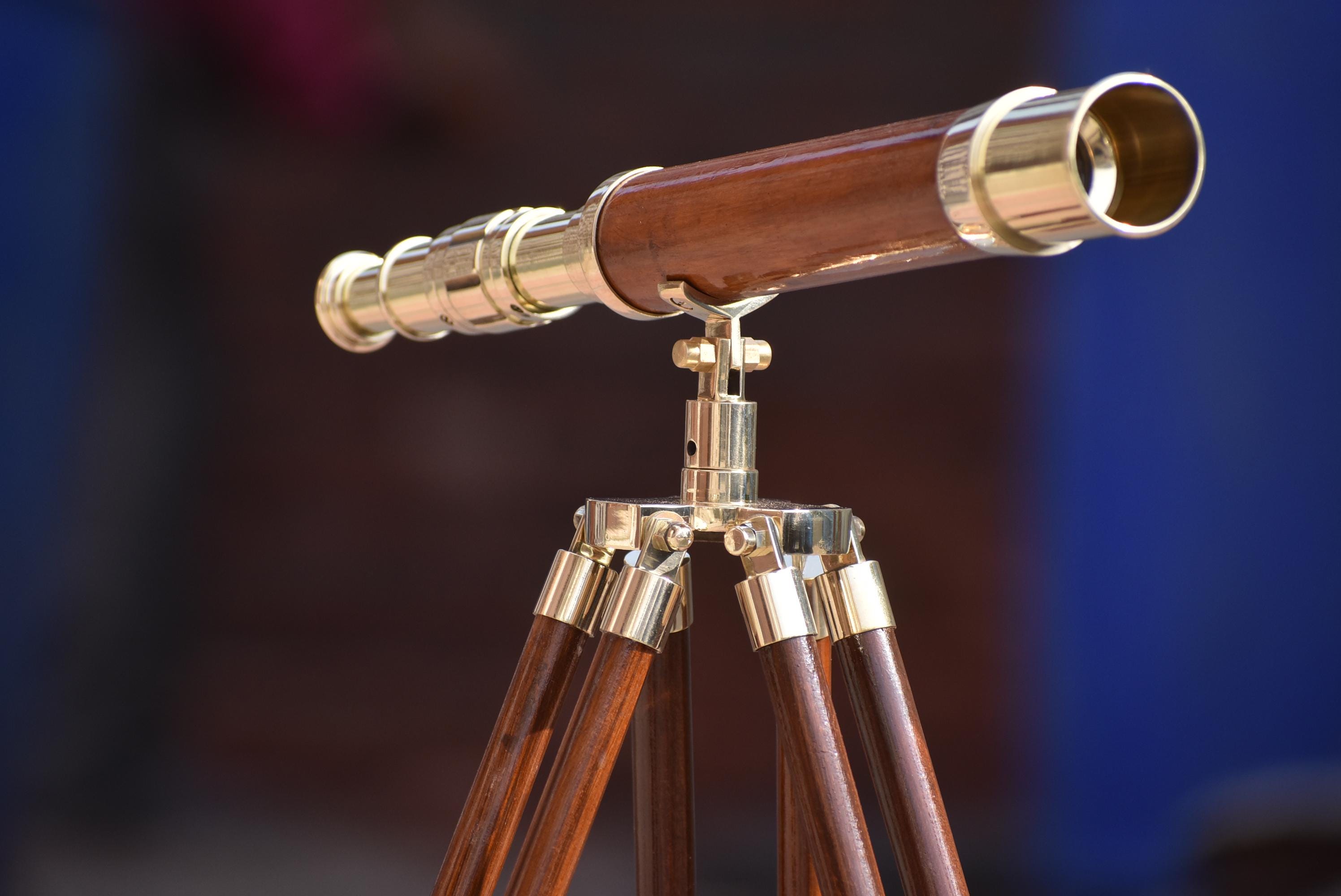 May include: A vintage telescope with a dark brown wooden barrel and brass detailing. It is mounted on a wooden tripod with brass fittings, evoking a classic nautical style. The telescope is a decorative item.