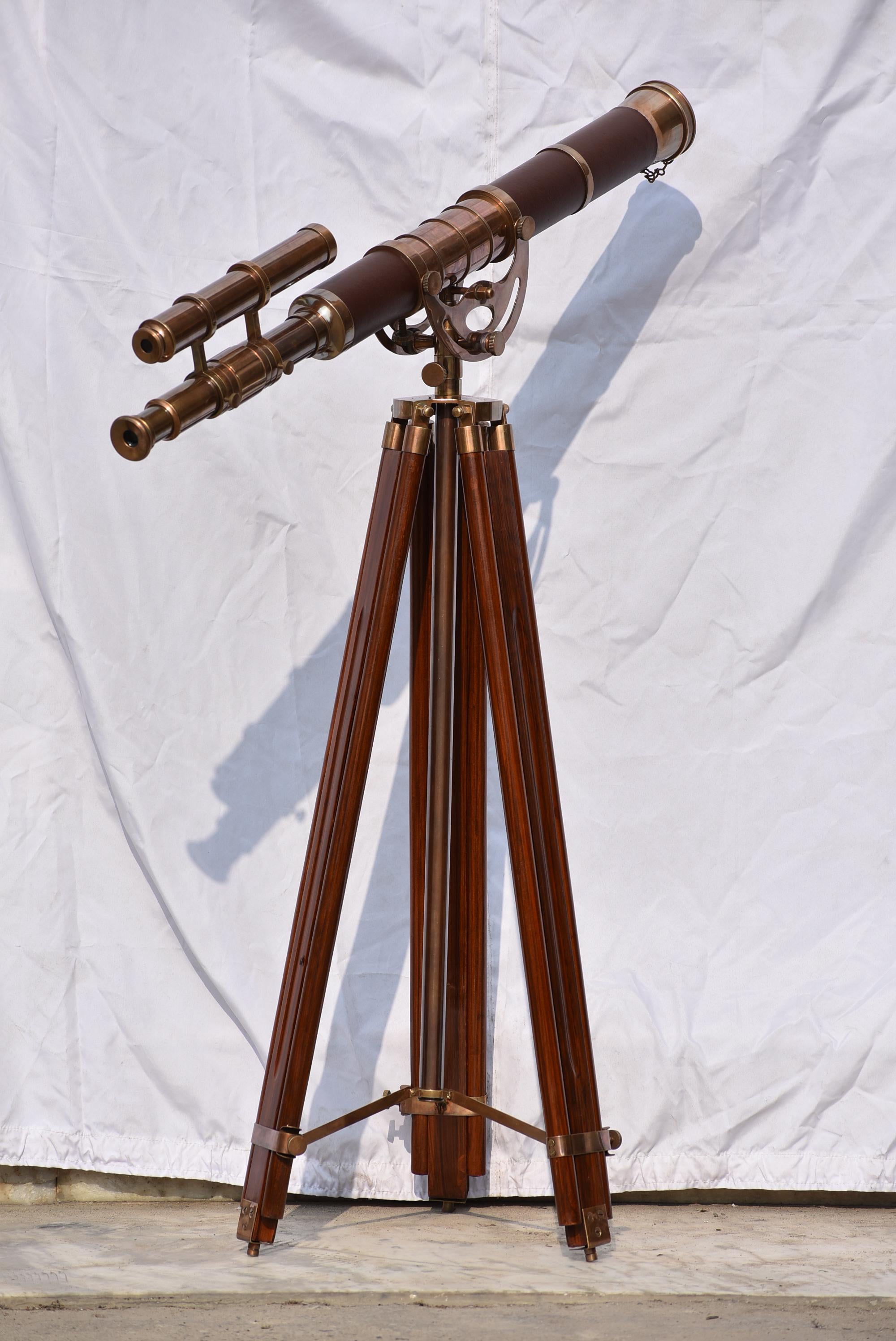 May include: A vintage-style telescope with a dark brown barrel and brass accents. It is mounted on a wooden tripod with brass fittings. The telescope has a smaller spotting scope attached to it.