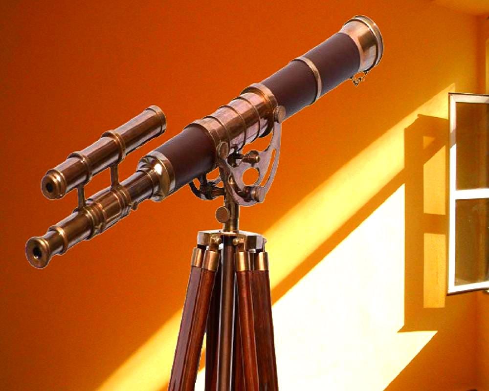 May include: A vintage-style telescope with brass accents and a dark brown barrel, mounted on a wooden tripod. The telescope has a secondary scope attached. The background is a warm orange with a window casting shadows.