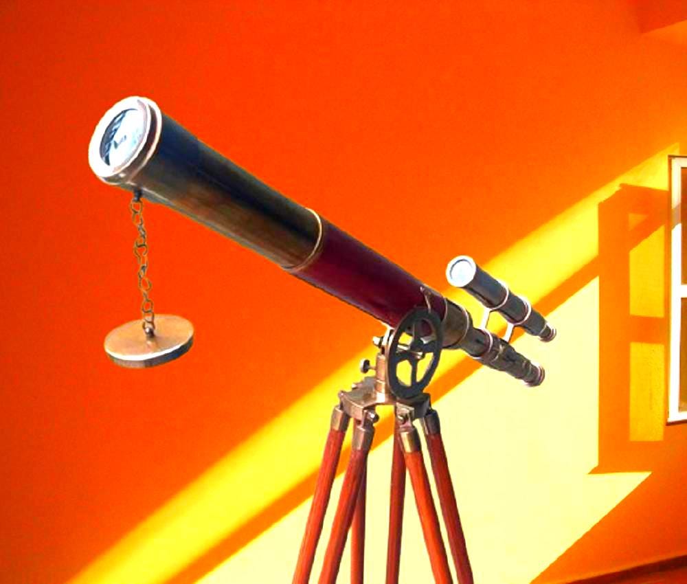 May include: A classic telescope with a brass and burgundy finish, set on a wooden tripod. It features a secondary scope and a lens cap attached by a chain. The background is a bright orange.