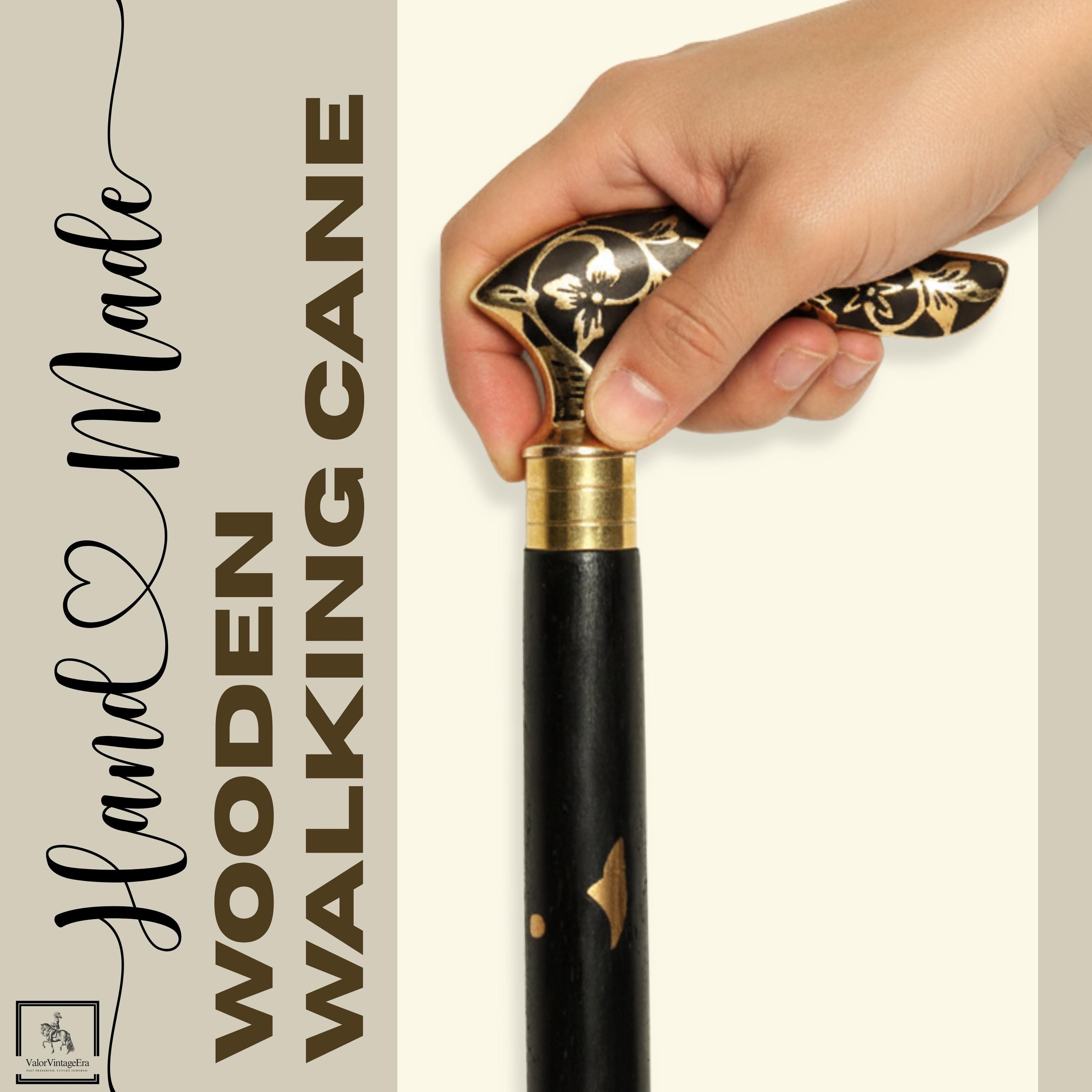 May include: Hand Made Wooden Walking Cane. The black wooden cane features a gold-colored floral design on the handle and a gold-colored band at the top. The cane has a black shaft with gold accents. The text "Hand Made Wooden Walking Cane" is in the image.