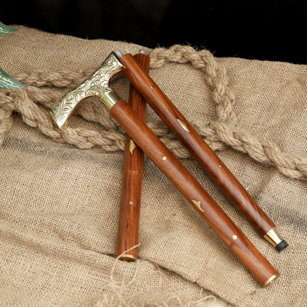 May include: A wooden walking cane with a decorative brass handle and accents. The handle features an ornate floral design. The cane is brown with brass details and a black rubber tip. The cane is approximately 91 cm long.