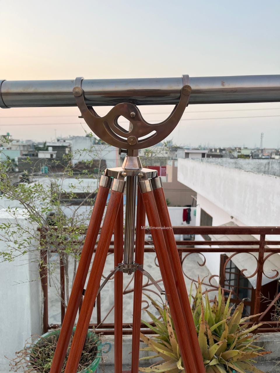 Può includere: Un telescopio in stile vintage con finitura in ottone e argento, montato su un treppiede in legno. Il corpo del telescopio è argentato e le gambe del treppiede sono marrone scuro. Il design evoca un'estetica nautica classica.