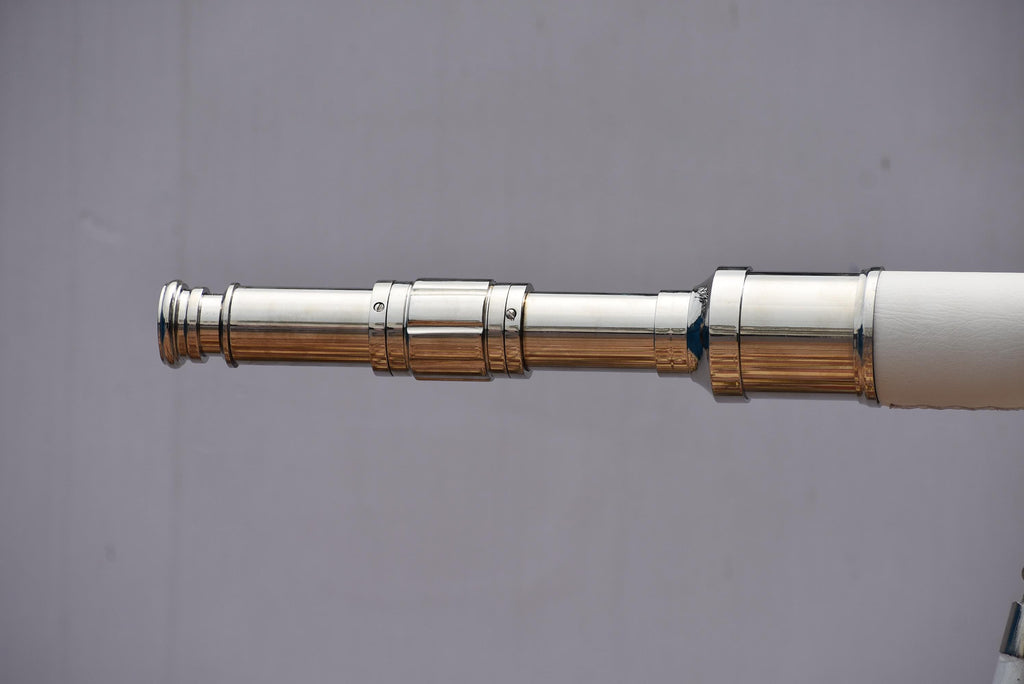 Può includere: Un telescopio argentato lucido con un'impugnatura bianca. Il telescopio è esteso e presenta più sezioni con un design dettagliato. Lo sfondo è di colore grigio.